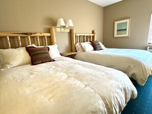 Two beds with headboards, a nightstand, a lamp, and a framed picture on the wall.