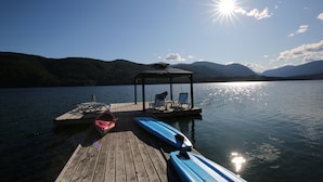 A wooden dock extending into a calm lake with a gazebo and lounge chairs.