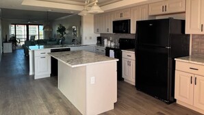 Una cocina amplia con armarios blancos, un refrigerador negro y una isla grande.