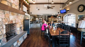 A restaurant interior with a stone fireplace, wooden ceiling beams, and a large window. - Updated and renovated Hideaway Apartment with new kitchen! Charming! (Gordonville)