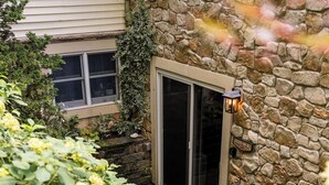 A stone exterior wall with a sliding glass door leading to a covered patio area. - Updated and renovated Hideaway Apartment with new kitchen! Charming! (Gordonville)