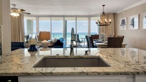 A kitchen with a large island, a view of the ocean, and a dining area with outdoor seating. - Tower 1, 2nd Floor, 2Bdr/2Bath!! Beautifully Remodeled!! FREE BEACH CHAIRS!! (Panama City Beach)