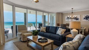 A spacious living room with a large window overlooking the ocean, a ceiling fan, and a view of the beach. - Tower 1, 2nd Floor, 2Bdr/2Bath!! Beautifully Remodeled!! FREE BEACH CHAIRS!! (Panama City Beach)