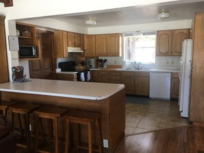 Enjoy cooking in this well-equipped kitchen with a central island and bar stools, featuring a microwave, stove, sink, and dishwasher.