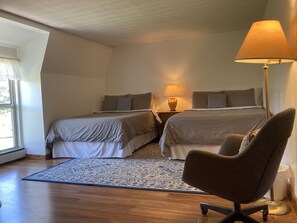 Two single beds with matching bedding, a bedside table, and a large window.