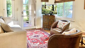 Ein Wohnzimmer mit einer Couch, einem Ledersessel, einem Fernseher und einem gemusterten Teppich.