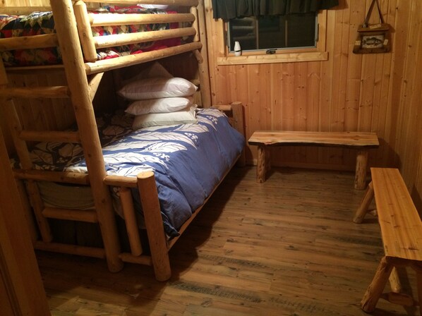 A wooden bunk bed with a blue bedspread, a wooden bench, and a small table. - Private, Renovated Lakefront Cottage, Lake Namakagon, Chequamegon Nat. Forest (Cable)
