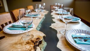 Een eettafel gedekt met borden, bestek en wijnglazen, klaar voor een maaltijd.