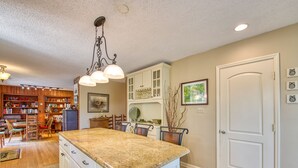 A kitchen with a granite countertop, white cabinetry, and a dining area with a wooden table and chairs.