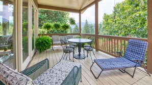 A covered outdoor patio with a round table and chairs, a sofa, and a blue patterned chair.