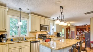 A spacious kitchen with a large island, stainless steel appliances, and a dining area with bar stools.