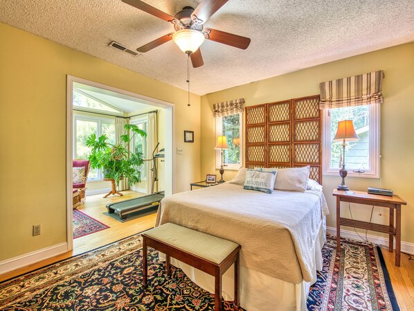 A bedroom with a bed, a bench, a nightstand, a lamp, a ceiling fan, and a window with curtains. - Enjoy a peaceful stay in the mountains of North Carolina at Lake Junaluska! (Lake Junaluska)