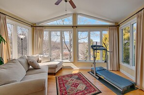 A sunroom with a large window, a treadmill, and a beige sofa. - Enjoy a peaceful stay in the mountains of North Carolina at Lake Junaluska! (Lake Junaluska)