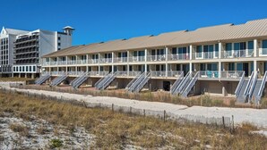 Een strandhotel met meerdere balkons, een zandstrand ervoor en een helderblauwe lucht.