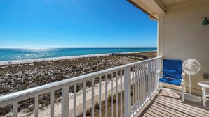 Een balkon met uitzicht op strand en zee.
