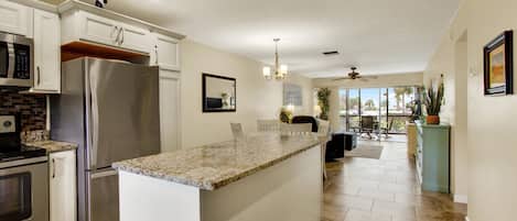 A modern kitchen with stainless steel appliances, a granite countertop island, and a dining area with a view.