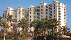 Ein mehrstöckiges Hotel mit einheitlicher Fassade, umgeben von Palmen.