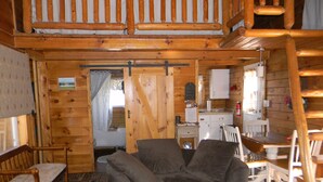 A cozy cabin interior with a wooden chair, a small table, and a kitchenette area. - Secluded Cabin on the Hill in the Hocking Hills (Laurelville)