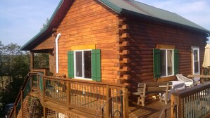 A wooden cabin with a deck, green shutters, and a small porch area. - Secluded Cabin on the Hill in the Hocking Hills (Laurelville)