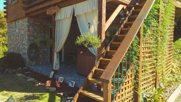A rustic wooden staircase leading to a stone building with a covered porch and a hanging planter. - Secluded Cabin on the Hill in the Hocking Hills (Laurelville)