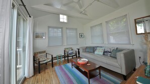 A spacious living room with a sofa, a wooden coffee table, and a colorful striped rug.