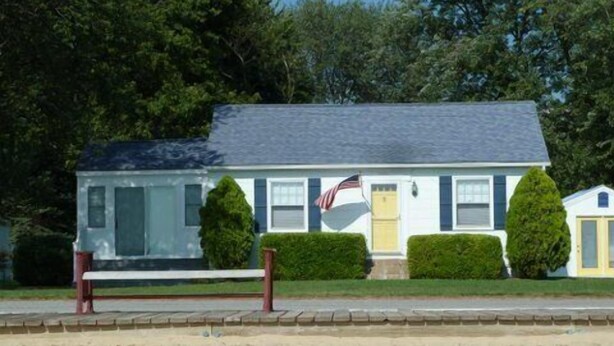 A single-story house with a front porch, a small attached garage, and a flag in front.