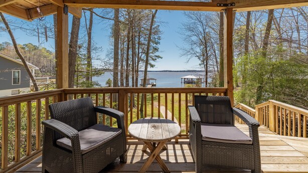 Terraza de madera con mobiliario de mimbre y vista a un lago.