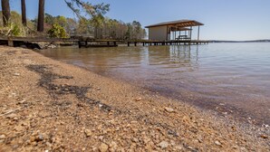 Una playa con un muelle de madera que lleva a una zona de estar cubierta.