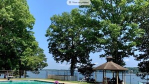 Una piscina con agua cristalina, rodeada de árboles y un pabellón.