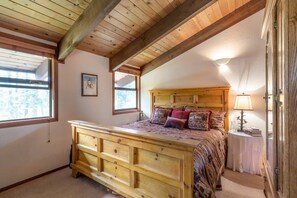 A bedroom with a wooden bed, a nightstand, a lamp, and a window. - Sleeps 10-Hot tub-Filtered lake views-Quiet neighborhood (Tahoe City)