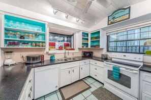 A kitchen with white cabinets, a microwave, a toaster, and a sink. - Su Casa - Beachfront Home - Indian Rocks Beach (Indian Rocks Beach)