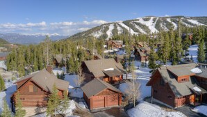 A cluster of log cabins with snow-covered roofs, surrounded by trees and a mountain backdrop. - Ski-In/Ski-Out Powder Ridge Cabin In Beautiful Big Sky (Big Sky)