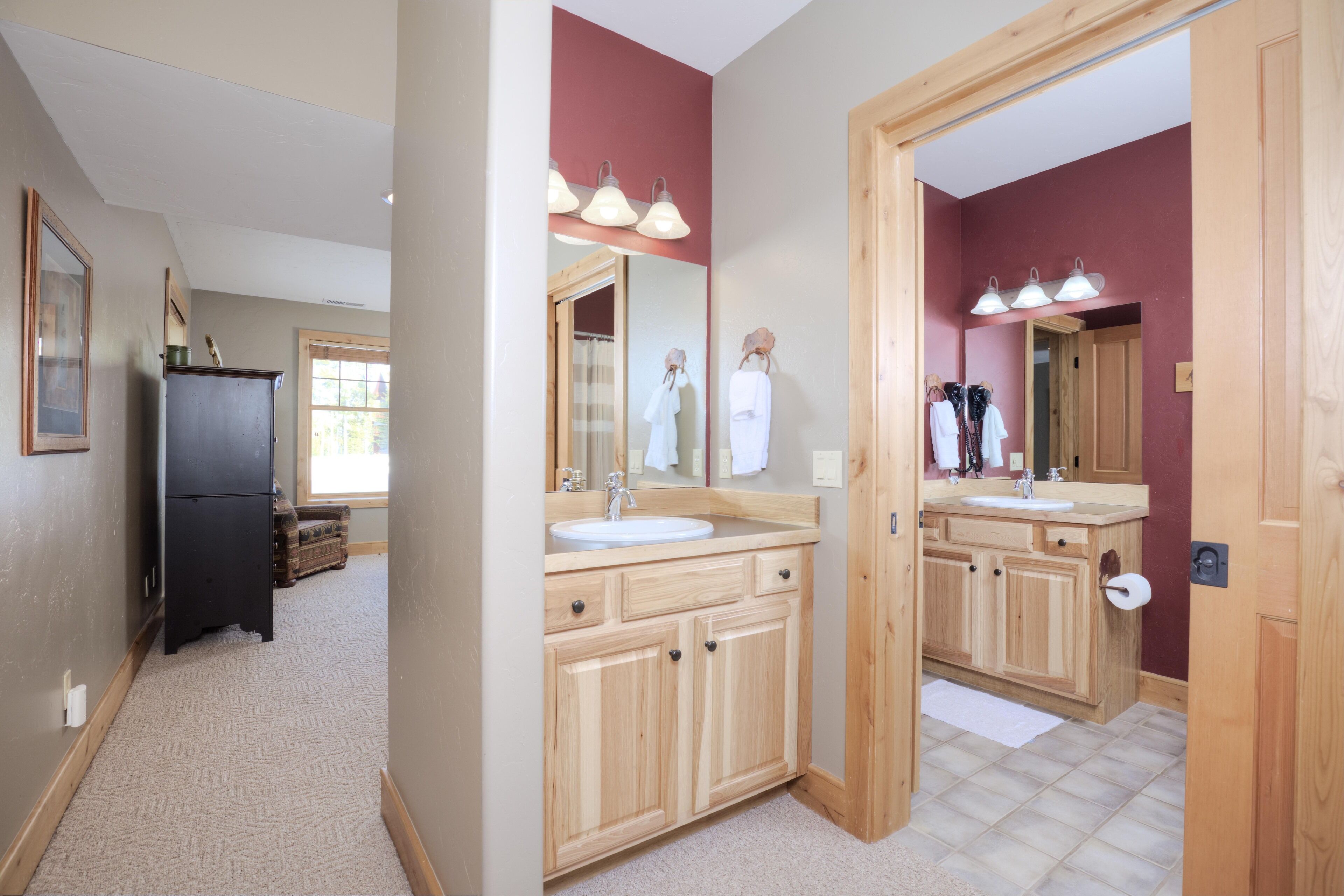 A spacious bathroom with wooden cabinets, a large mirror, and a sink.