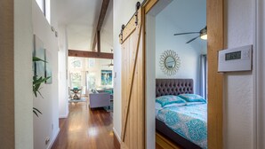 A bedroom with a bed, a ceiling fan, and a thermostat.