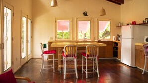 Eine Küche mit Holzausstattung, einem weißen Kühlschrank und einem Essbereich mit drei Stühlen und einem Tisch.