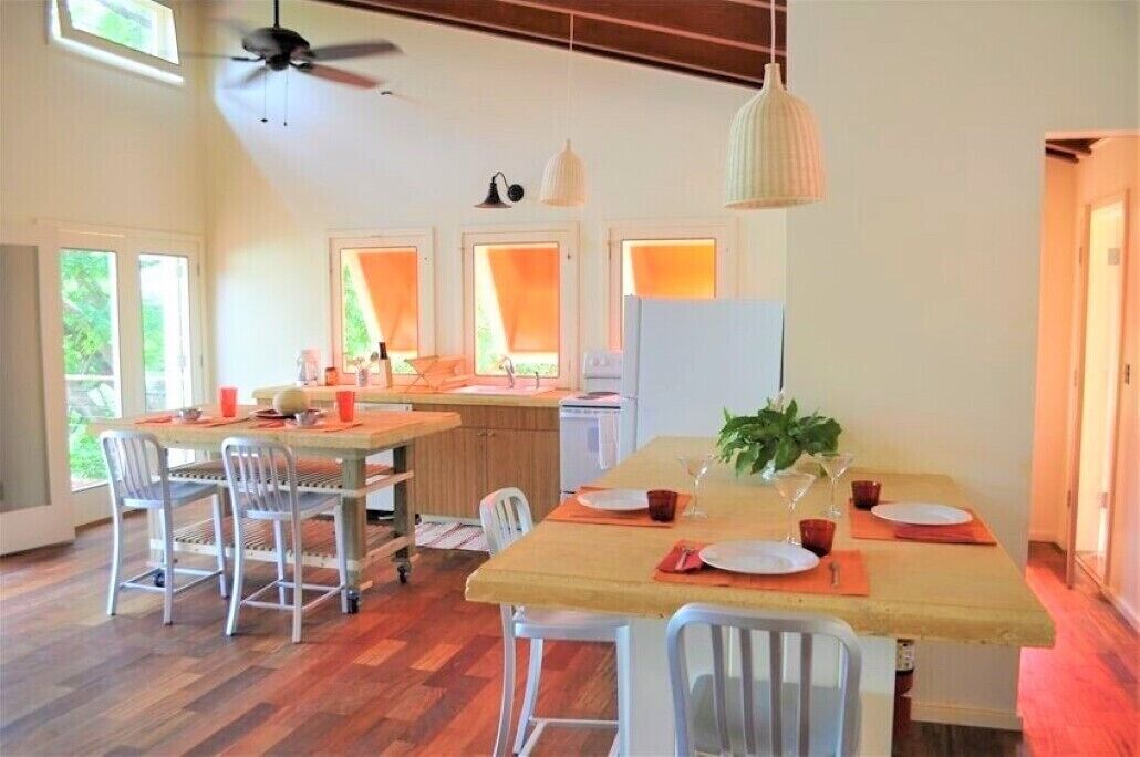 A spacious dining area with a long table, chairs, and a ceiling fan.