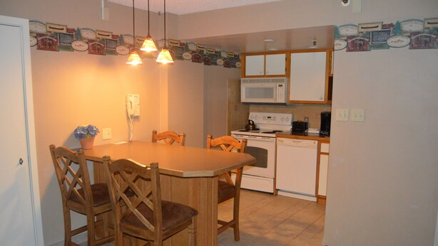A compact kitchen with a dining table, chairs, a microwave, and a stove.