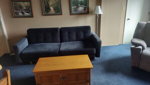 A living room with a dark blue sofa, a wooden coffee table, and a lamp.
