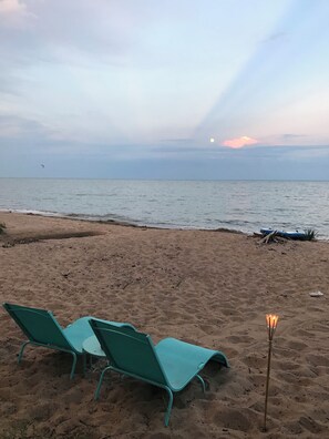 Une plage avec deux chaises longues turquoise et un petit foyer.