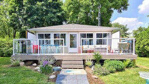 A modern house with a covered porch, outdoor furniture, and a garden. - Prepare to fall in love with this adorably tropical beach front property! (Kingsville)