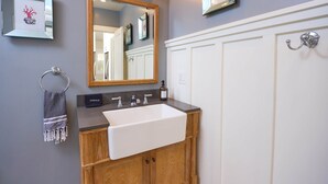A bathroom with a wooden vanity, a white sink, a mirror, and a towel rack.