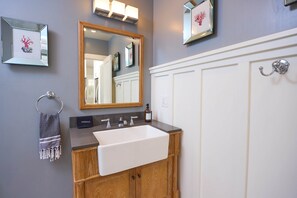 A bathroom with a wooden vanity, a white sink, a mirror, and a towel rack.