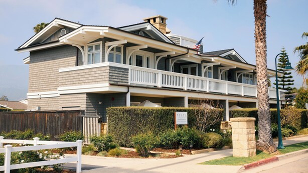 A two-story building with a balcony, a flag, and a sign that reads 'PLAYA.'
