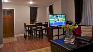 A living room with a television, a dining table, and a coffee table with books and a vase of flowers. - Luxury Homebase in Downtown Boulder  (Boulder)