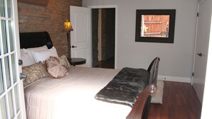 A bedroom with a bed, a bench, a lamp, and a window with a view of a wooden structure. - Luxury Homebase in Downtown Boulder  (Boulder)