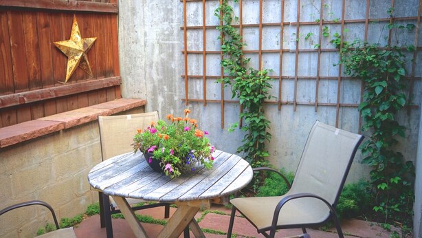 A round wooden table with a potted plant, two chairs, a star decoration on a wooden wall, and a trellis with climbing plants. - Luxury Homebase in Downtown Boulder  (Boulder)
