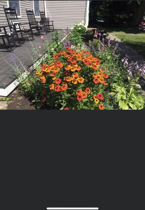 Enjoy the serene garden view from the deck, surrounded by vibrant flowers and lush greenery.