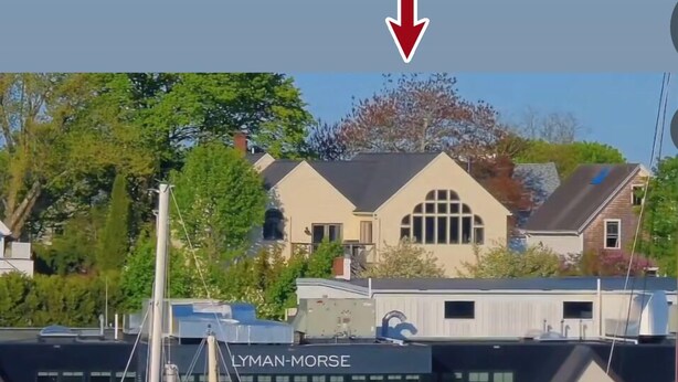 Un port de plaisance avec des bateaux amarrés, un bâtiment portant l’inscription « LYMAN-MORSE », et une zone résidentielle en arrière-plan.