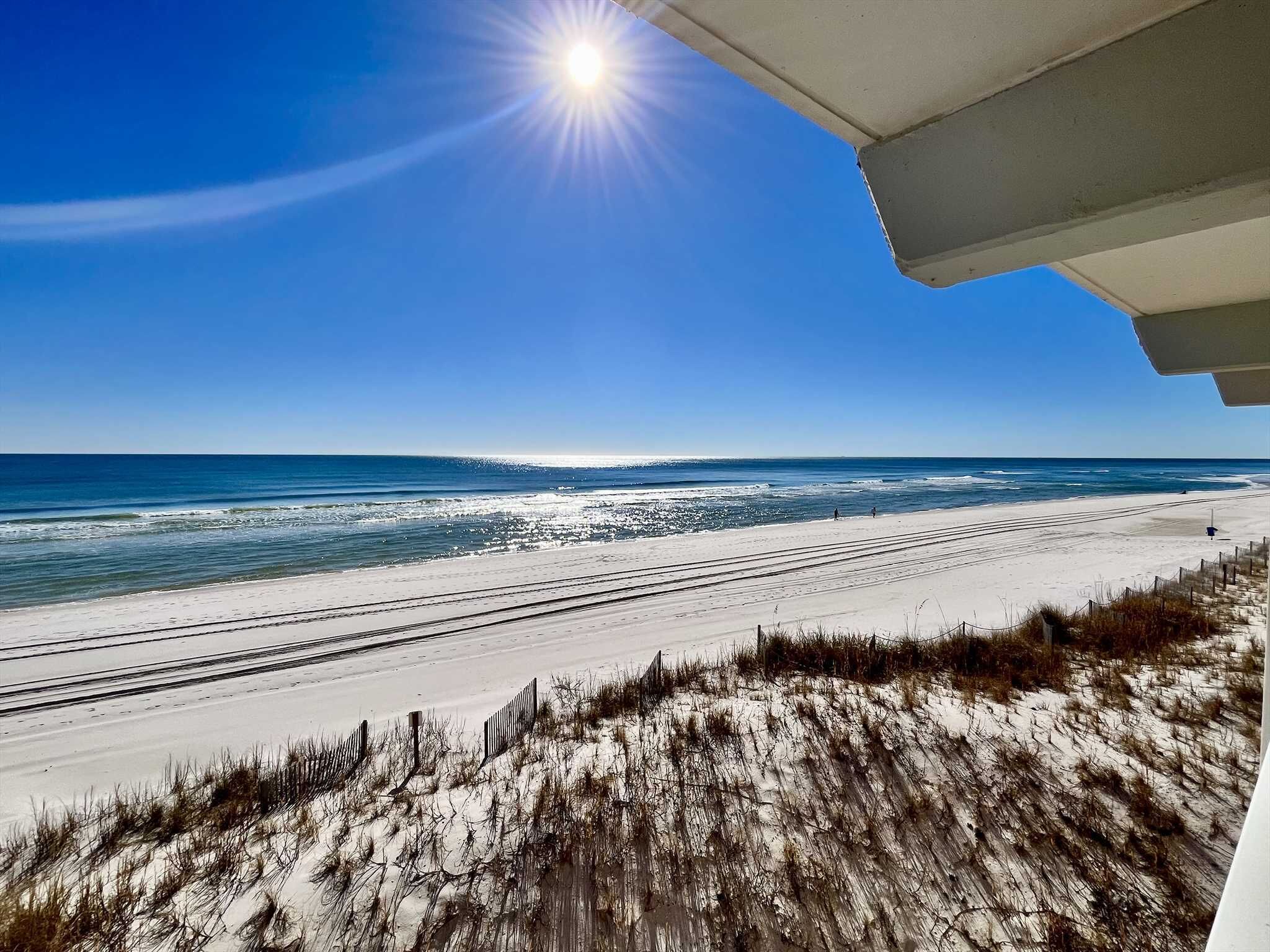 A beach with a clear sky, ocean waves, and a sandy shore.