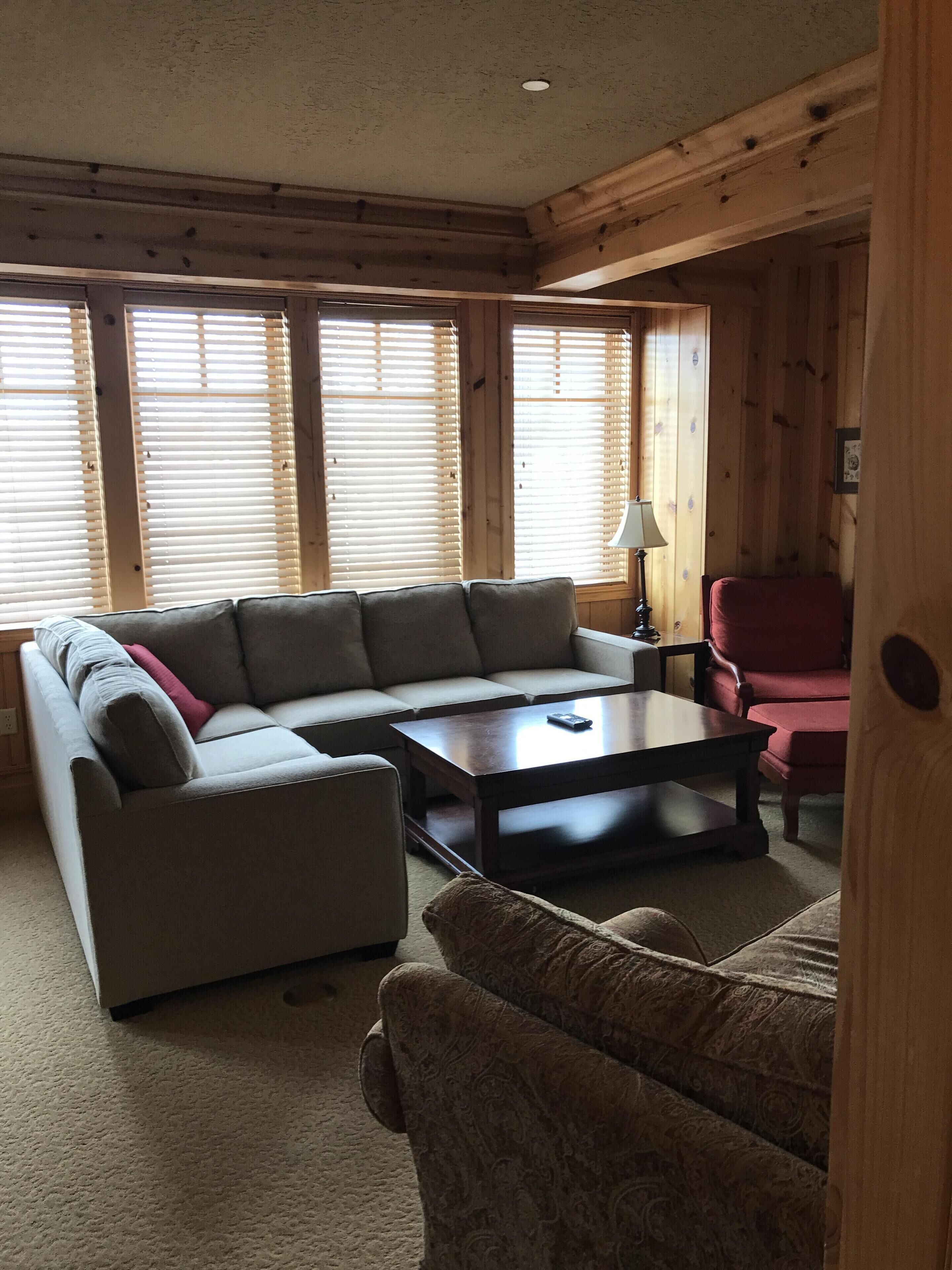A cozy living room with a sectional sofa, a coffee table, and a red armchair.